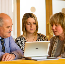 Three people sitting around a tablet computer
